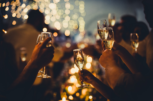 Numerous hands holding champagne flutes with champagne celebratory toast silhouettes