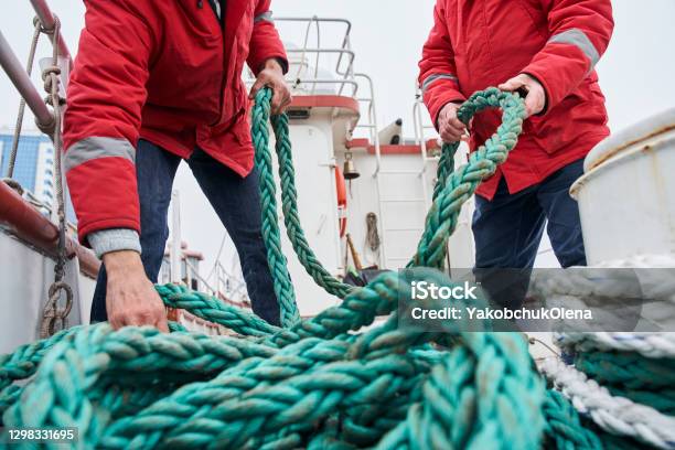 Two Male Colleagues Fishermans Pulling Rope On Deck Of A Boat Stock Photo - Download Image Now