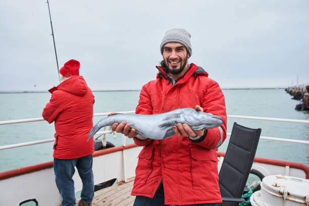 istock Fisherman showing his catch while standing at the deck 1298331717