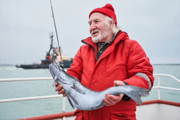istock Fisherman standing at the deck and holding his fish catch 1298331742