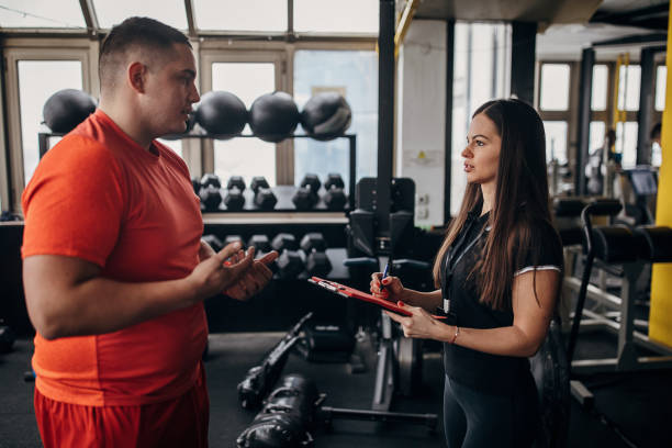 istock Man talking with female personal trainer in gym 1298332141