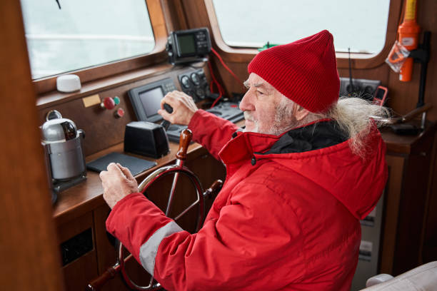 istock Man holding hands on steering wheel and navigating sailboat 1298334242