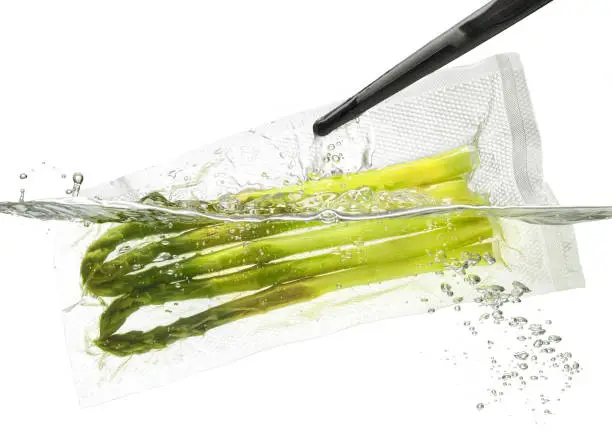 Asparagus for sous vide cooking, taking out or putting into the water; isolated on white background