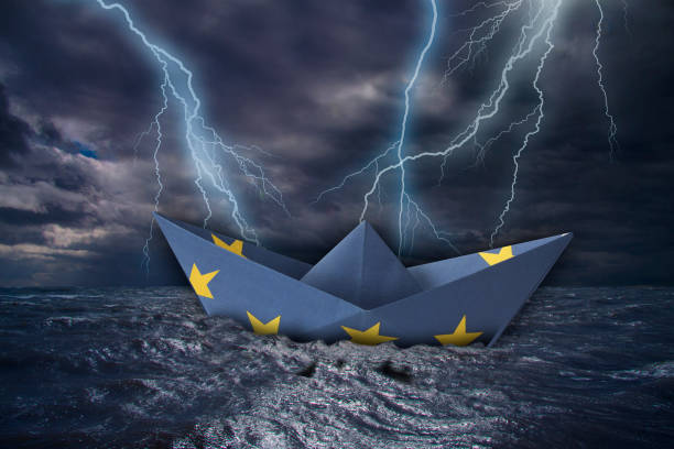 barco de papel de la ue fabricado como la bandera de la unión europea casi se al voltea en altas olas y rayos - rain wind crisis business fotografías e imágenes de stock