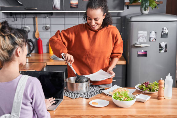istock Girl pouring pasta at plate from her friend while cooking 1298342105