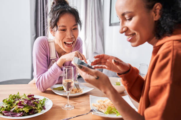istock Girls laughing while looking at smartphone during dinner 1298342305