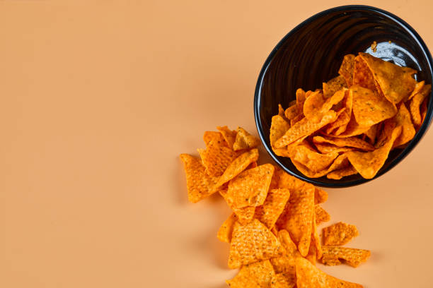 istock Bowl of crispy chips on orange background 1298344809