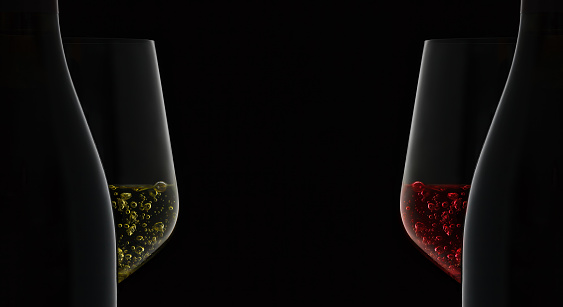 Closeup of bottle and wineglass with white wine on black background.