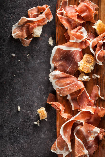 Italian ham raw. Slices of Prosciutto on dark  background. Top view. prosciutto stock pictures, royalty-free photos & images