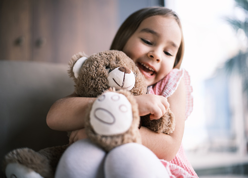 Little Child Girl Hugging Her Toy Bear At Home Nearby Window