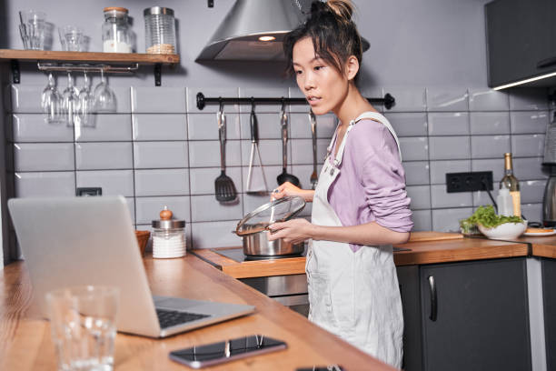 istock Woman covers pan with a lid while looking attentively recipe 1298348399
