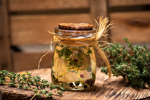 Fresh garden Thyme essential oil and herb on a rustic table closeup. Healthy plants and herbal medicine abstract