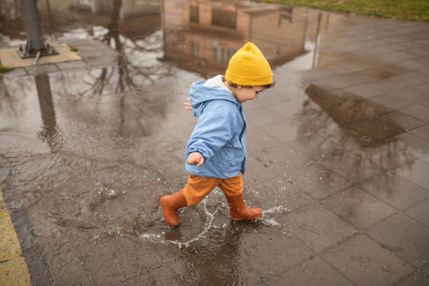 istock Playful child having fun running over puddles on autumn day 1298349419