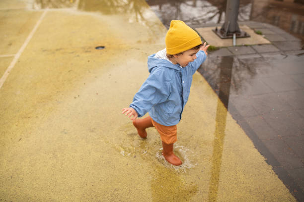 istock Little boy having fun in puddle in schoolyard 1298349526
