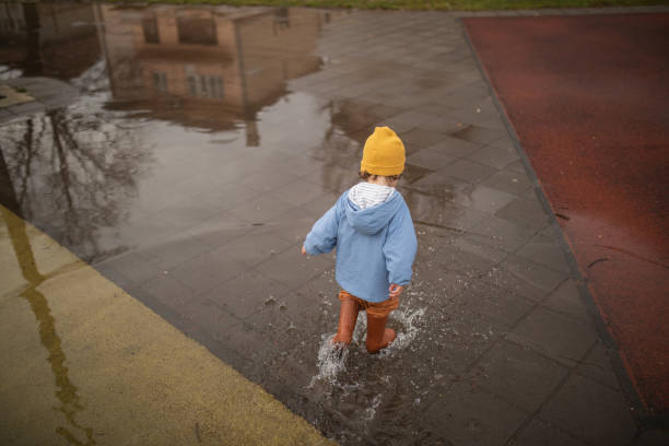 istock Little boy walking over puddle at schoolyard 1298350532
