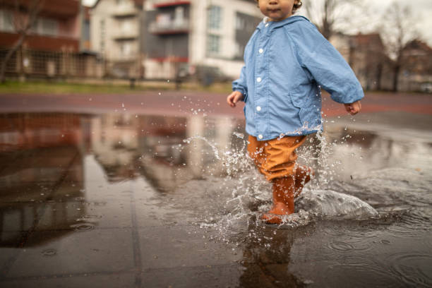 istock Playful child having fun running over puddles on autumn day 1298350809