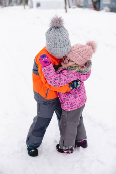 istock Two children hugging and playing in the snow 1298351538