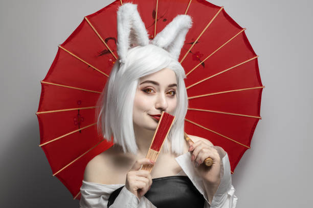 Blonde girl in a wig on a gray background with an umbrella, cosplay cat women. stock photo