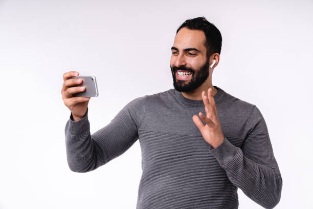 istock Handsome Arabian man using smartphone for online conversations and video calls isolated over white background 1298353867