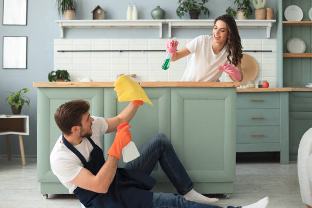 istock Young happy couple is having fun while doing cleaning at home. 1298354157