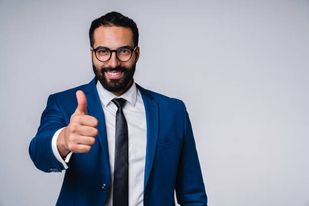 istock Cheerful young middle eastern businessman showing thumb up isolated over grey background 1298354206