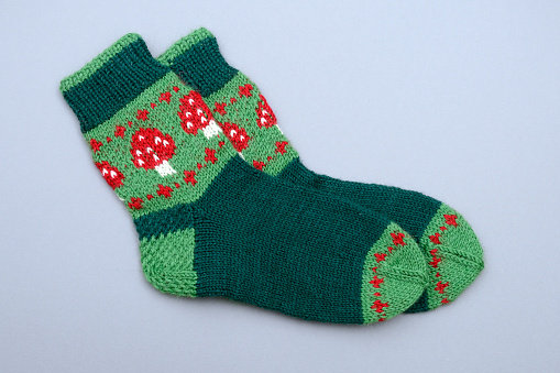 a woolen socks with amanita print on neutral background