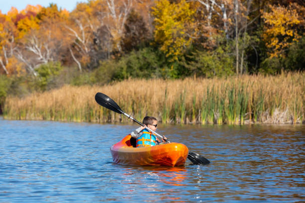 istock Young Boy In Orange & Yellow Kayak on Lake 1298355578