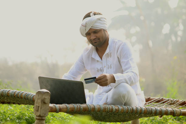 istock Indian farmer on laptop doing payment by using credit card - concept of rural people using technology, internet and lifestyle.turban 1298355614