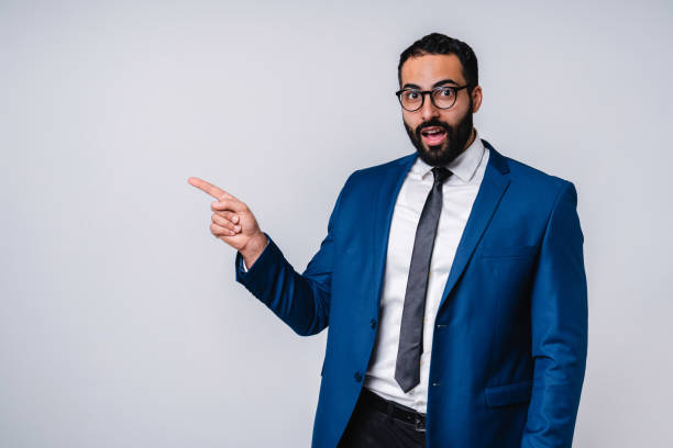istock Surprised Arab man pointing at copy space in formal clothes isolated over grey background 1298355729