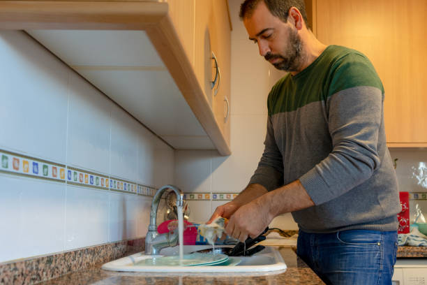 istock Bearded man washing dishes in his home kitchen 1298358238