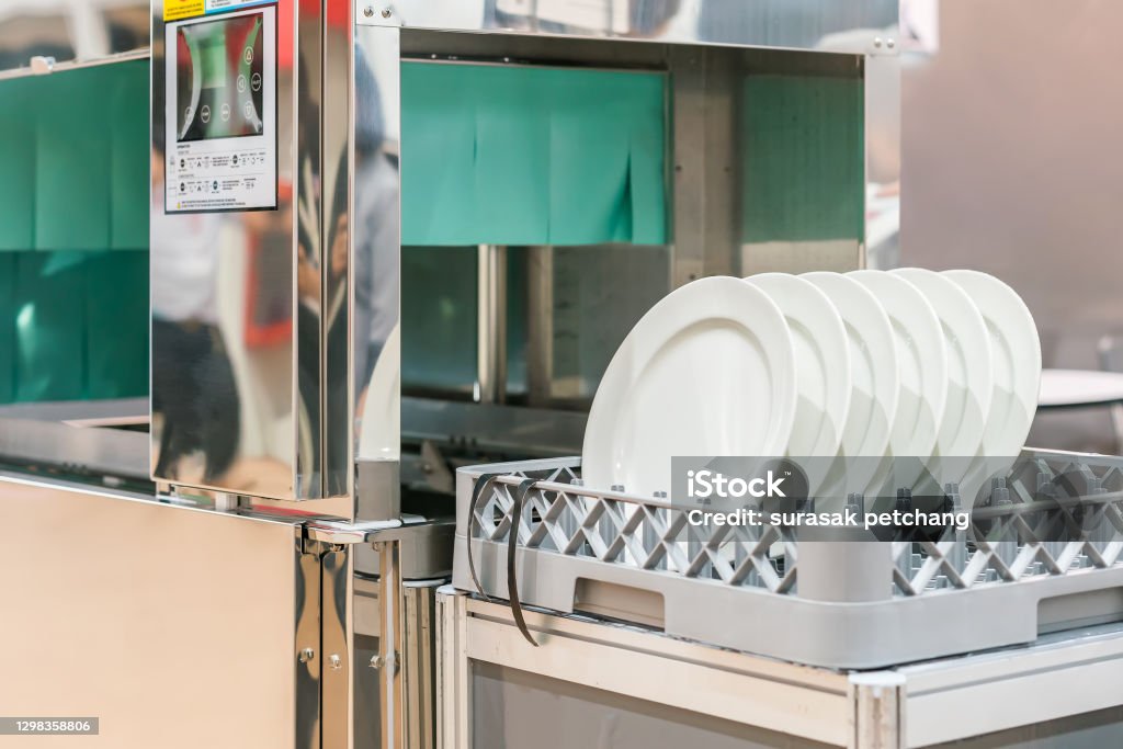 many white plate on basket in automatic dishwasher machine for cleaning in kitchen room restaurant Dishwasher Stock Photo