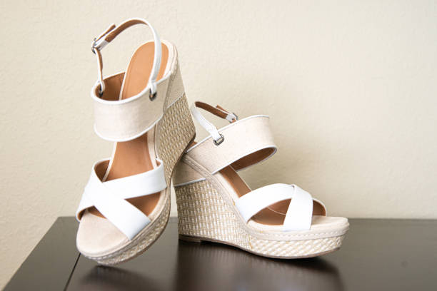 istock Bride's white open toe wedge sandals with straps stacked on wood surface 1298360082