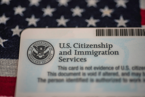 Washington, DC, USA - July, 16, 2018: Back side of employment (work) authorization card by US Citizenship and Immigration Services (USCIS) on American flag background.