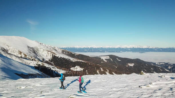 speikkogel - un drone ha sparato a una coppia che indossava scarpe da neve che si aggirava fino alla vetta di amerinkogel nelle alpi austriache. neve fresca in polvere - snowshoeing hiking mountain winter foto e immagini stock