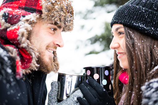 An attractive couple in love is having tea and enjoying a snowy day out