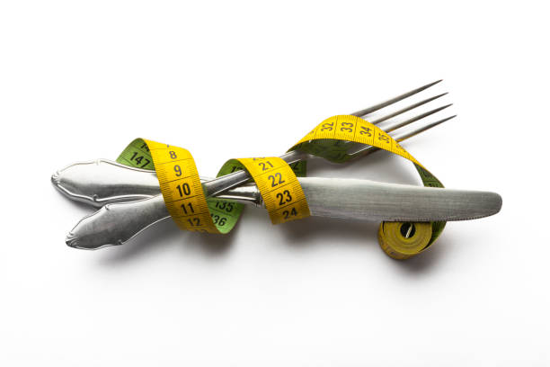 Knife and Fork Joined with a Tape Measure stock photo