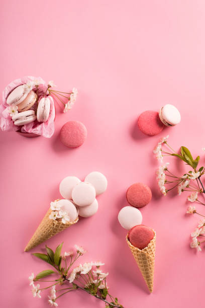 istock Rose macaroons in gift box and Cherry blossoms. Sweet macarons present on pink background. 1298368052