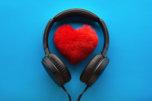 Red heart and black headphones on a blue background. Love music lifestyle concept. Valentine's Day
