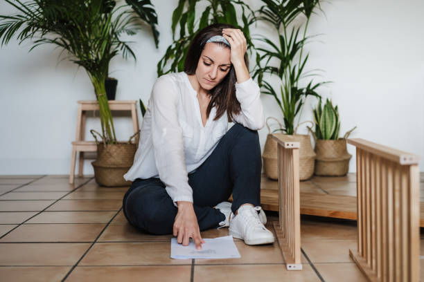 istock young woman assembling furniture at home reading instructions. DIY concept 1298368954