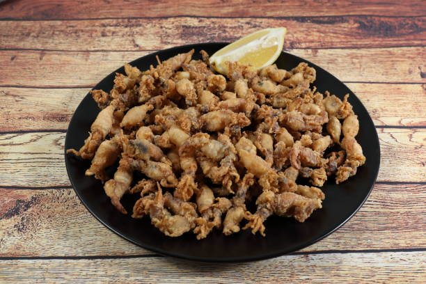 istock Ration of fried chopitos (squid tips) in black plate on rustic wooden table 1298372136