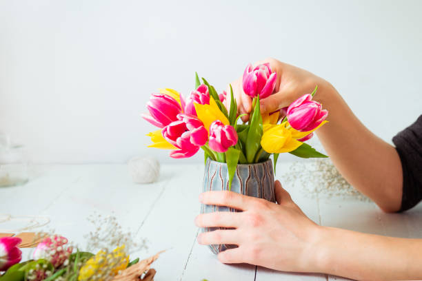 istock No face young man making spring bouquet using tulips. Online self-education of floristry. Learning flower arranging. Flowers delivery. Male florist creating order. Selective focus. 1298375502