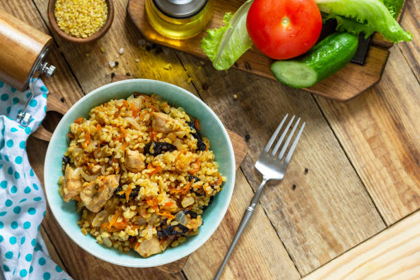 istock Bulgur with turkey and prunes is served with fresh vegetable on a rustic table. Top view flat lay. Copy space. 1298376022
