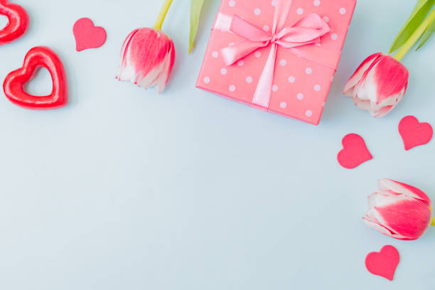 istock Flat lay valentines day frame with pink tulips and gift box on a light green background 1298376088