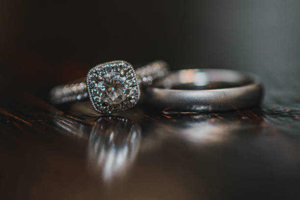 istock Silver wedding rings with diamonds on wood reflective surface 1298376453