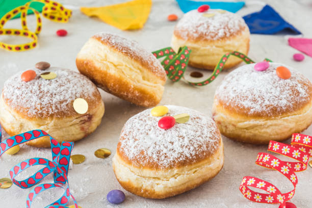 istock Krapfen, Berliner or donuts with streamers, confetti and chocolate beans on white background. Colorful carnival or birthday image. 1298378123