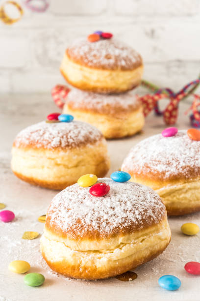istock Carnival powdered sugar raised donuts with paper streamers, confetti and chocolate beans on white background, vertical 1298378349