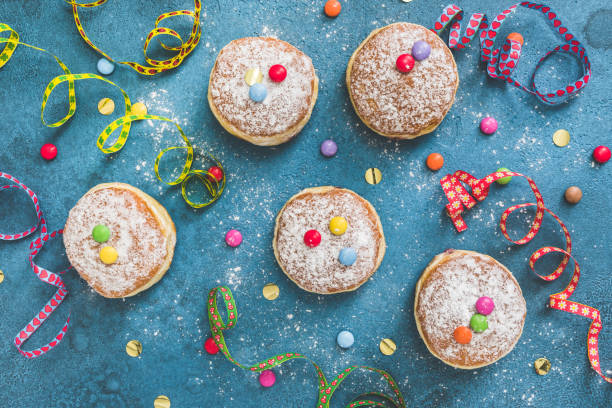 Homemade Bugnes are little golden doughnuts sprinkled with icing sugar, sweet and crispy, prepared for Mardi gras . Served in a jar with colored paper napkin, confetti and colombina carnaval masks in the background