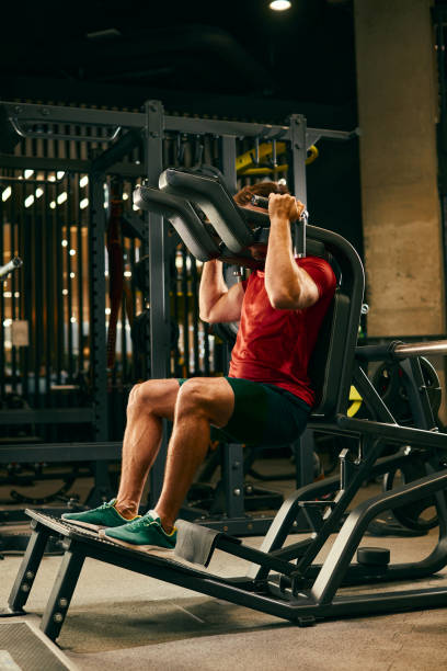 istock Athletic man doing legs exercise on squat machine at the gym 1298379127