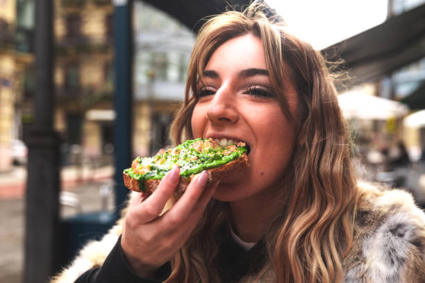 Young caucasian woman having breakfast at a terrace eating an avocado toast. Young caucasian woman having breakfast at a terrace eating an avocado toast. dipping sauce photos stock pictures, royalty-free photos & images