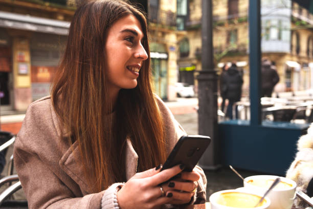 istock Young caucasian woman using a mobile phone while having breakfast at a terrace on a winter morning 1298380056